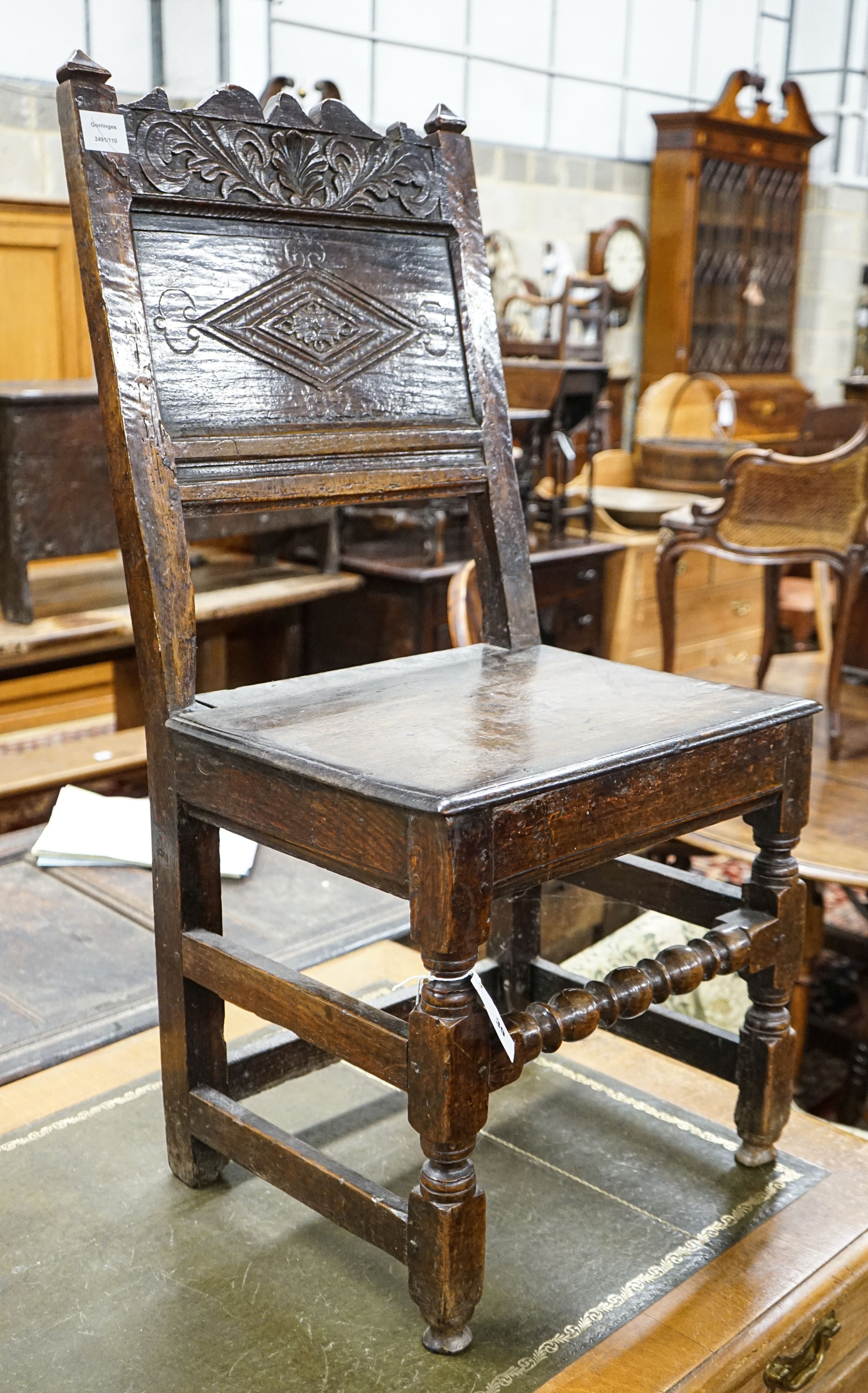 A 17th century oak back stool, with lozenge and foliate carved panelled back and solid seat, on turned and square underframe, width 48cm, depth 40cm, height 97cm, with receipt from Swan Antiques dated 2002